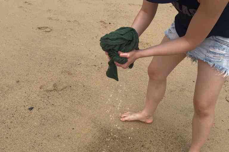 Wringing the PackTowl Luxe out at a beach after soaking it in seawater.