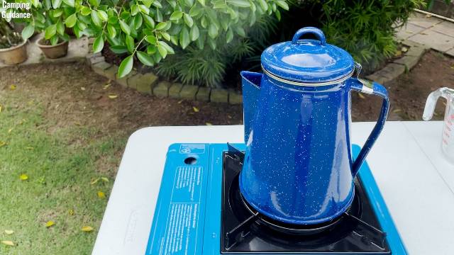 Steam coming out of the spout of the Stansport 8-Cup Enamel Percolator while brewing coffee outdoors on the Coleman Portable Butane Stove.