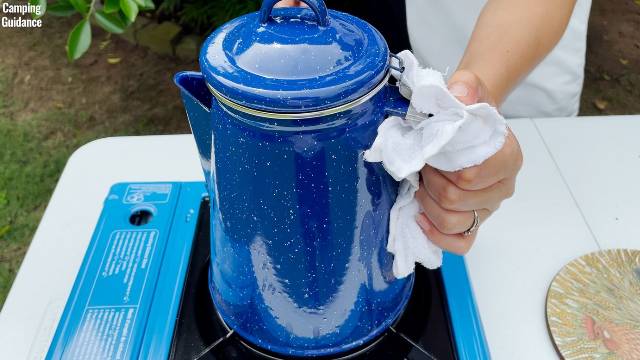 Using a cloth to hold the handle of the Stansport Enamel 8-Cup Percolator.