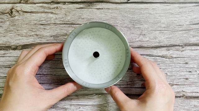 Lining the Coletti Bozeman Camping Percolator's filter basket with the provided coffee filter paper.