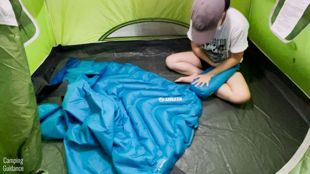 This is a picture of me inflating the Klymit Double V Uninsulated Sleeping Pad by using my free hand to press down on its stuff sack.