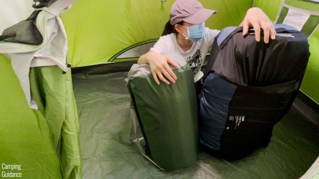 This is a picture of me sitting inside a tent with the Exped MegaMat Duo 10 Medium (left) and the REI Camp Dreamer Double (right).