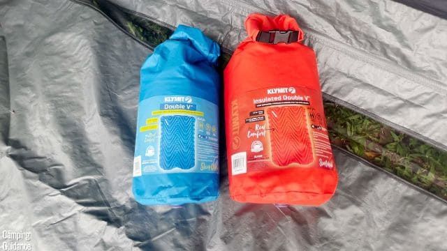 This is a picture of the packed up Klymit Uninsulated Double V (left) beside the Klymit Insulated Double V (right) on the ground.