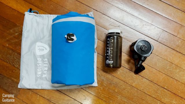 This shows the rolled-up Sierra Designs 2-Person Camping Air Mattress beside a 32-ounce Nalgene bottle and the included pump for a size comparison.