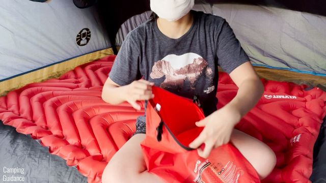 This is a picture of me holding the roll-top stuff sack of the Klymit Double V Insulated Sleeping Pad to show that it's a bit tight.