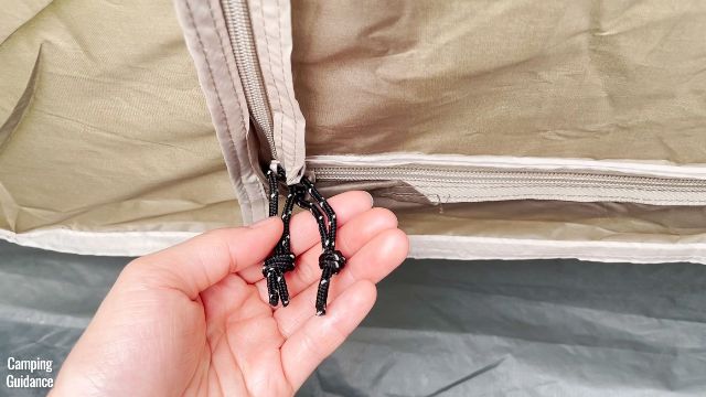 This is a picture of me holding the 2 black door zippers of the back door of the Coleman WeatherMaster 10-Person Tent.
