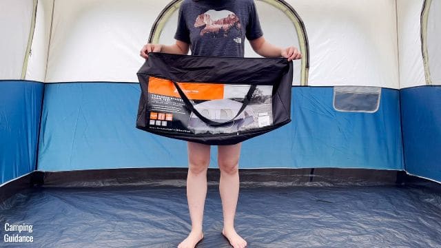 This is a picture of me holding the empty carry bag of the Ozark Trail 10-Person Cabin Tent. 