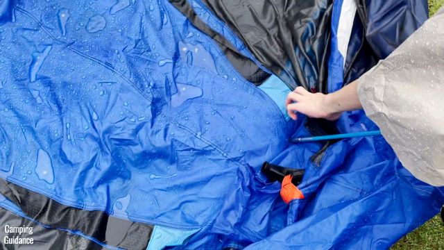 This is a picture of me inserting the blue roof poles of the Columbia Mammoth Creek Tent through the blue-tipped pole sleeves.