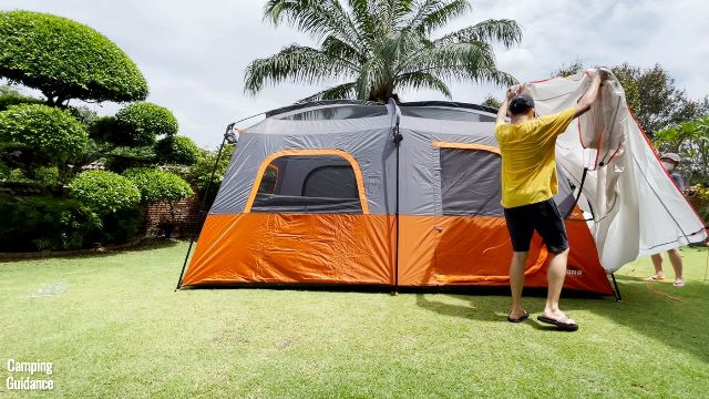 This is a picture of my brother and I draping the rainfly over the roof of the Core 10-Person Straight Wall Cabin Tent. The rainfly is white in color.