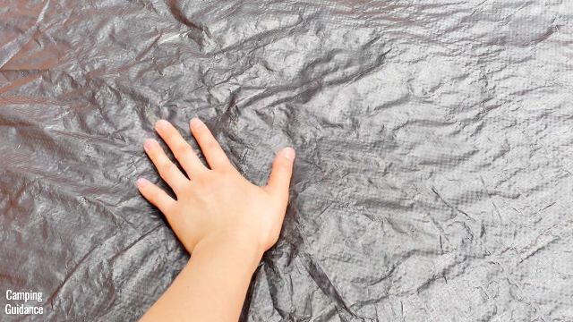 This is a picture of me touching the polyethylene flooring of the Core 10-Person Straight Wall Cabin Tent.