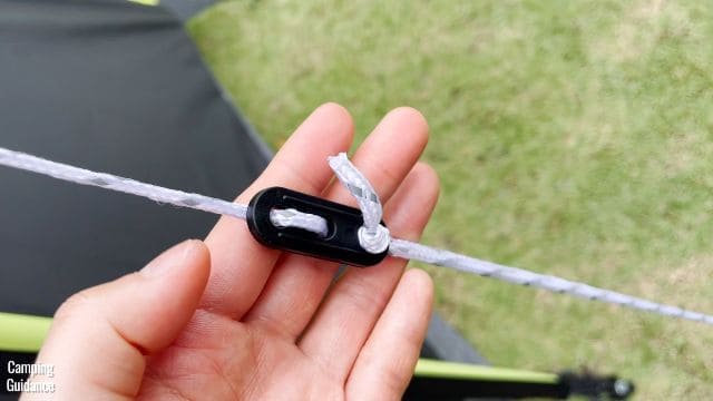 The guylines of the Coleman 10-Person Instant Cabin Tent are white, with a black tensioner in the middle.