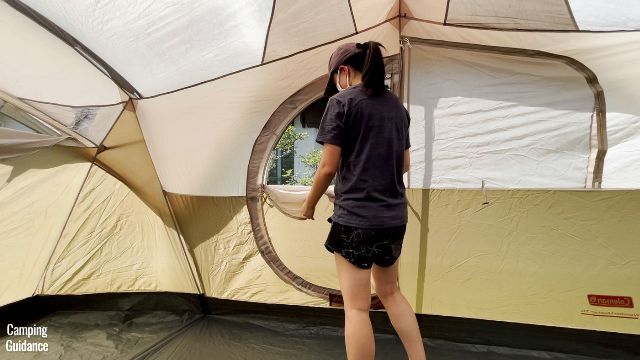 This is a picture of me unzipping the window mesh of the hinged D-door of the Coleman WeatherMaster 10-Person Tent.
