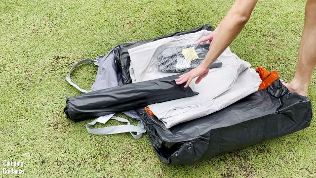In this picture, you can see the Core Straight Wall Cabin Tent's carry bag, tent body (black and orange), rainfly (white), poles in a black carry bag, plus other accessories.