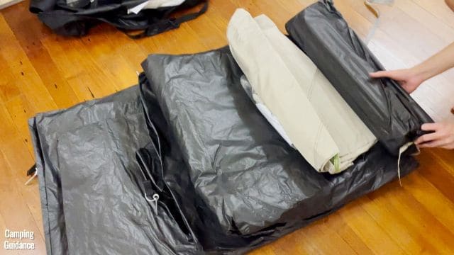 This is what the Ozark Trail 10-Person Cabin Tent, along with all relevant items, looked like when we first took it out of the box. In this picture, you can see the tent body on the floor, the rainfly on top of the tent body, and my brother holding a carry bag containing some poles for the tent.
