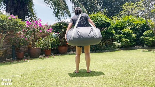 This is a picture of me carrying a packed up Core 10-Person Straight Wall Cabin Tent using the shoulder strap of the carry bag.