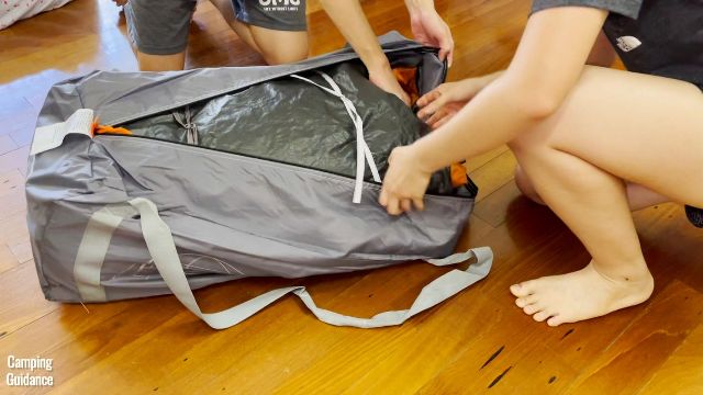 This is a picture of me packing up the Core 10-Person Straight Wall Cabin Tent back into the carry bag.