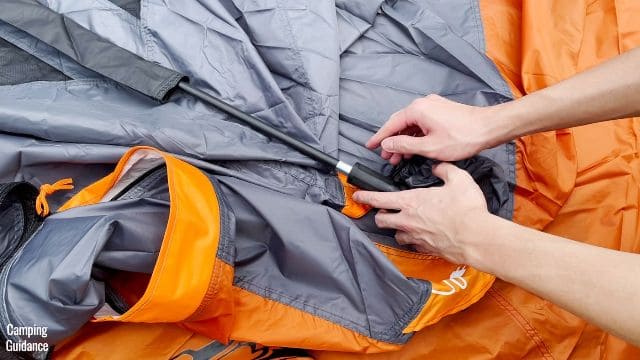 This is a picture of me connecting the black fiberglass roof pole to one of the pole joints on the roof of the Core 10-Person Straight Wall Cabin Tent.