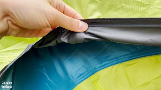 This is a picture of me grabbing the rainfly of the Coleman 10-Person Instant Cabin Tent.