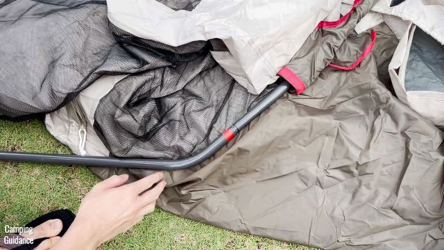 This is a picture of me attaching the straight steel poles with the red-colored band to the curved steel pole, to set up the Coleman WeatherMaster 10-Person Tent. 