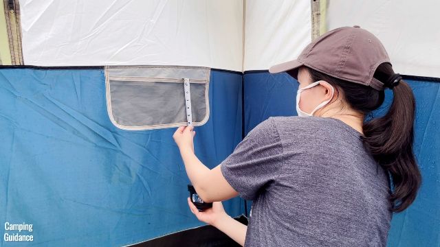 This is a picture of me using a tape measure to measure the dimensions of one of the storage pockets inside the Ozark Trail 10-Person Cabin Tent.