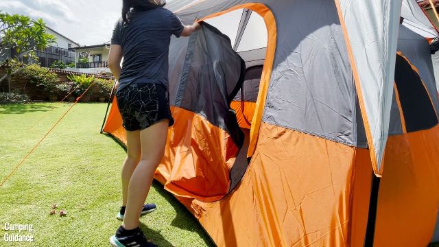 This is a picture of me unzipping one of the doors of the Core 10-Person Straight Wall Cabin Tent. 