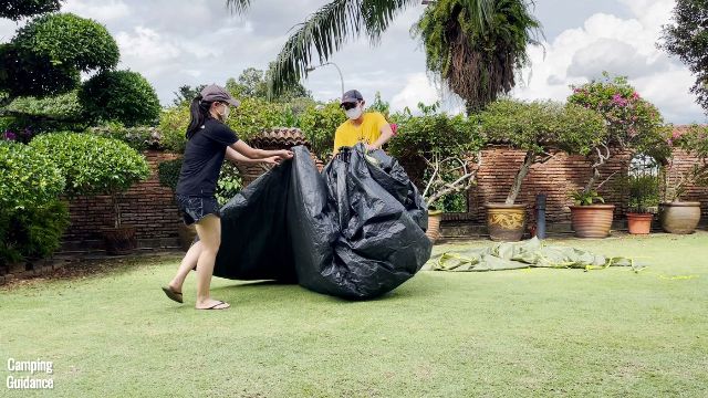 This is a picture of my brother and I packing up the Outdoor Products 10-Person Instant Cabin Tent. He's holding the center hub, and I'm folding up the fabric towards the center hub.