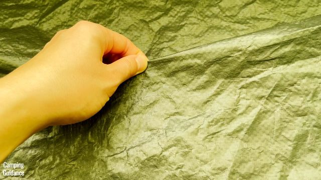 This is a picture of me pinching the polyethylene flooring of the Outdoor Products 10-Person Instant Cabin Tent.