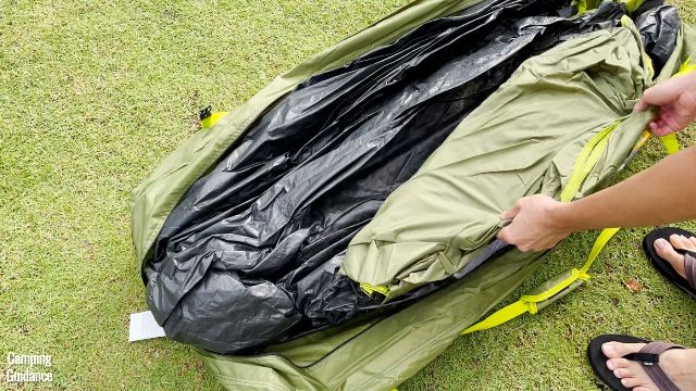 This is a picture of me holding the rainfly (green) of the Outdoor Products 10-Person Instant Cabin Tent. The tent body is in black, and both are still in the carry bag (also green).