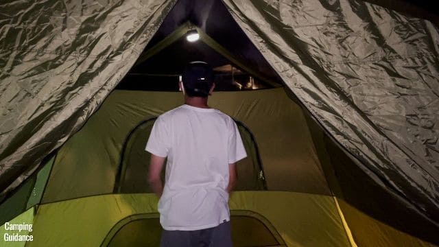 This is a picture of my brother hanging up a Black Diamond Moji lantern in one of the room’s lantern loops inside the Outdoor Products 10-Person Instant Cabin Tent.