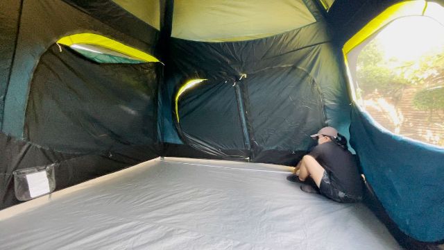 This is a picture of me using a tape measure to measure the width of the Coleman 10-Person Instant Cabin Tent.