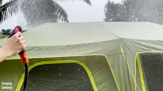 This is a picture of me spraying water on my Outdoor Products 10-Person Instant Cabin Tent., with a water hose.