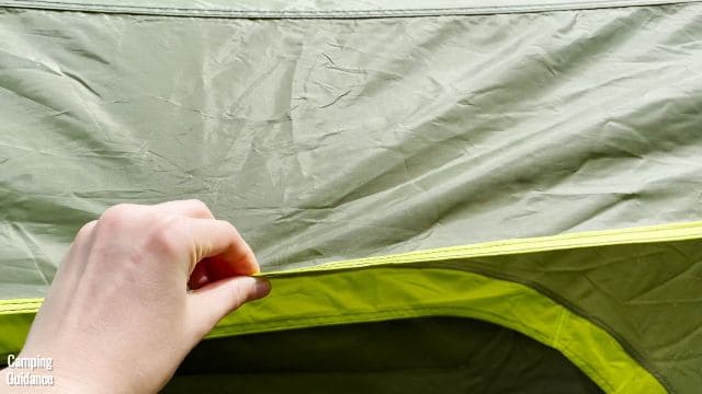 This is a picture of me touching the fabric of the rainfly of the Outdoor Products 10-Person Instant Cabin Tent.