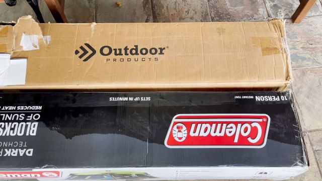 This is a picture showing the cardboard packaging of the Outdoor Products 10-Person Tent (top) and the Coleman 10-Person Instant Cabin Tent (bottom). Both are exactly the same size.