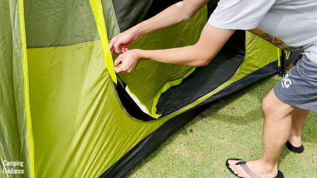 This is a picture of my brother opening up the side door of the Outdoor Products 10-Person Instant Cabin Tent from the outside. Notice how the door droops back into the tent.
