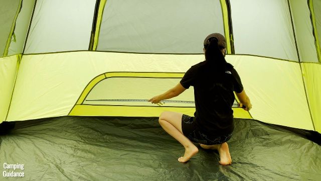 This is a picture of me using a tape measure to measure the dimensions of the ground vent inside the Outdoor Products 10-Person Instant Cabin Tent (59 by 11 inches).