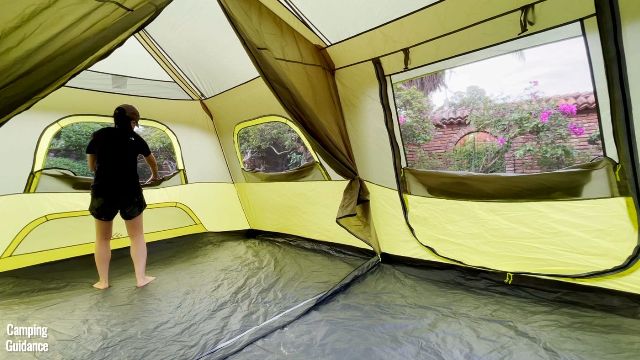 This is a picture of me opening up all the window and door mesh panels in the Outdoor Products 10-Person Instant Cabin Tent. From left to right, we have a window, another identical window, and the mesh panel from the side door.