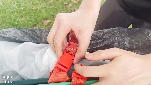 This is a picture of me undoing the red buckles of the Quechua 2 Seconds Pop Up Tent.