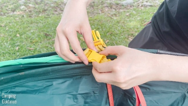 This is a picture of me undoing the yellow buckles of the Quechua 2 Seconds Pop Up Tent.
