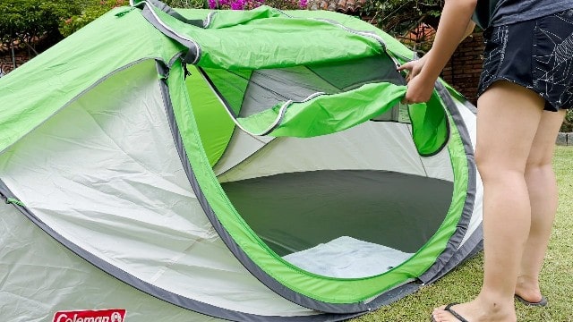 This is a picture of me unzipping the inner green window of the Coleman 4-Person Pop Up Tent. Notice that the door is laid out on top of the tent.
