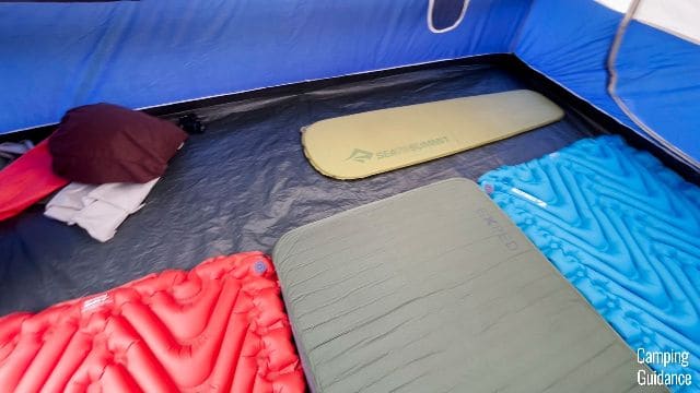 The Coleman Elite Sundome 6-Person Tent can fit 7 regular-sized sleeping pads. From left to right: Klymit Insulated Double V (red), Exped MegaMat Duo 10 (green), Klymit Uninsulated Double V (blue), Sea to Summit Camp Mat (yellow).