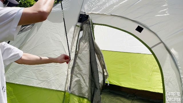 This is a picture of the shortest black fiberglass pole of the Coleman Montana 8-Person Tent being inserted into the straight part of the hinged D-door.
