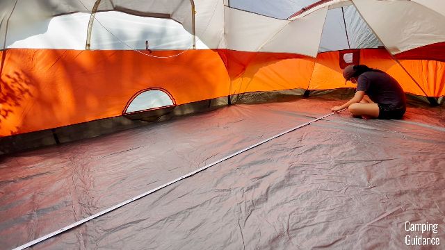 This is a picture of me using a measuring tape to measure the longest length of the Coleman Red Canyon 8-Person Tent (16 feet 4 inches).