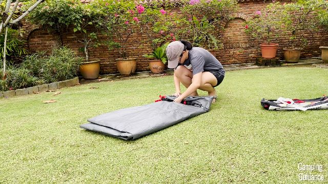 This is a picture of me packing up the Coleman Skydome Tent by rolling it up.