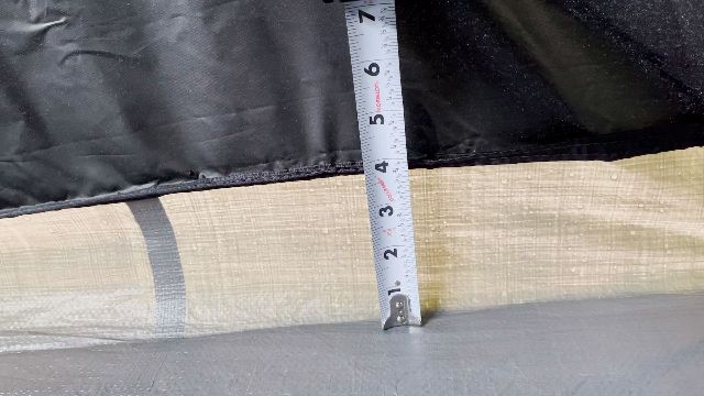 A close up shot of me using a tape measure to measure the height of the bathtub flooring in my Coleman 10-Person Instant Dark Room Tent (4 inches).