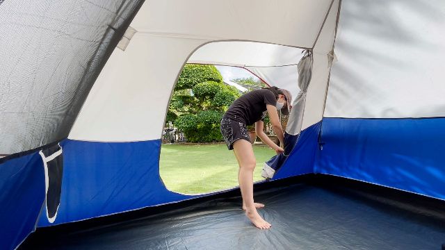 This is a picture of me latching the back door of the Coleman Elite Sundome Tent to the side to keep it open.