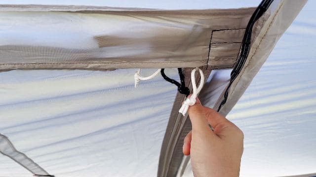 A close up shot of the hinged door zippers. The white zippers are for the window, and the black zippers are for the hinged door.