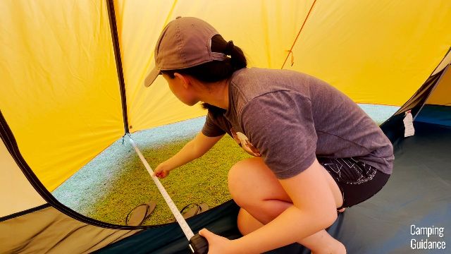 This is a picture of me measuring the width of the front vestibule of the REI Base Camp 6 (54 inches).