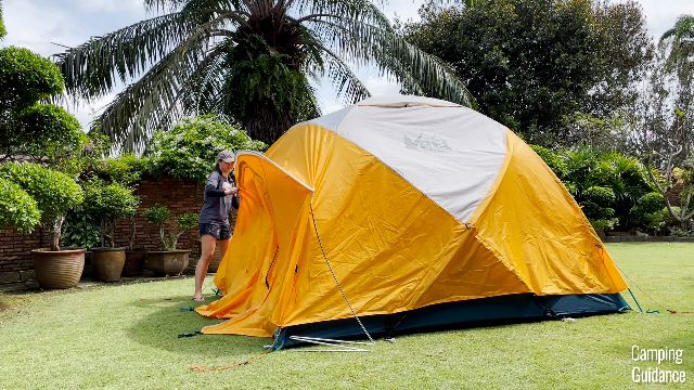 Me removing the white pole from the white pole sleeve of the REI Base Camp 6's rainfly.