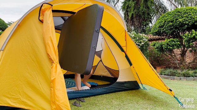Me taking my Exped MegaMat Duo 10 (fully inflated) out of the REI Base Camp 6 through one of the doors.