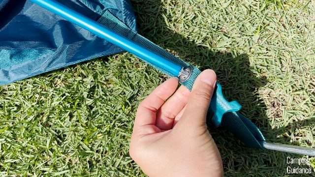 The tip of the blue pole goes into the grommet of the blue webbing.